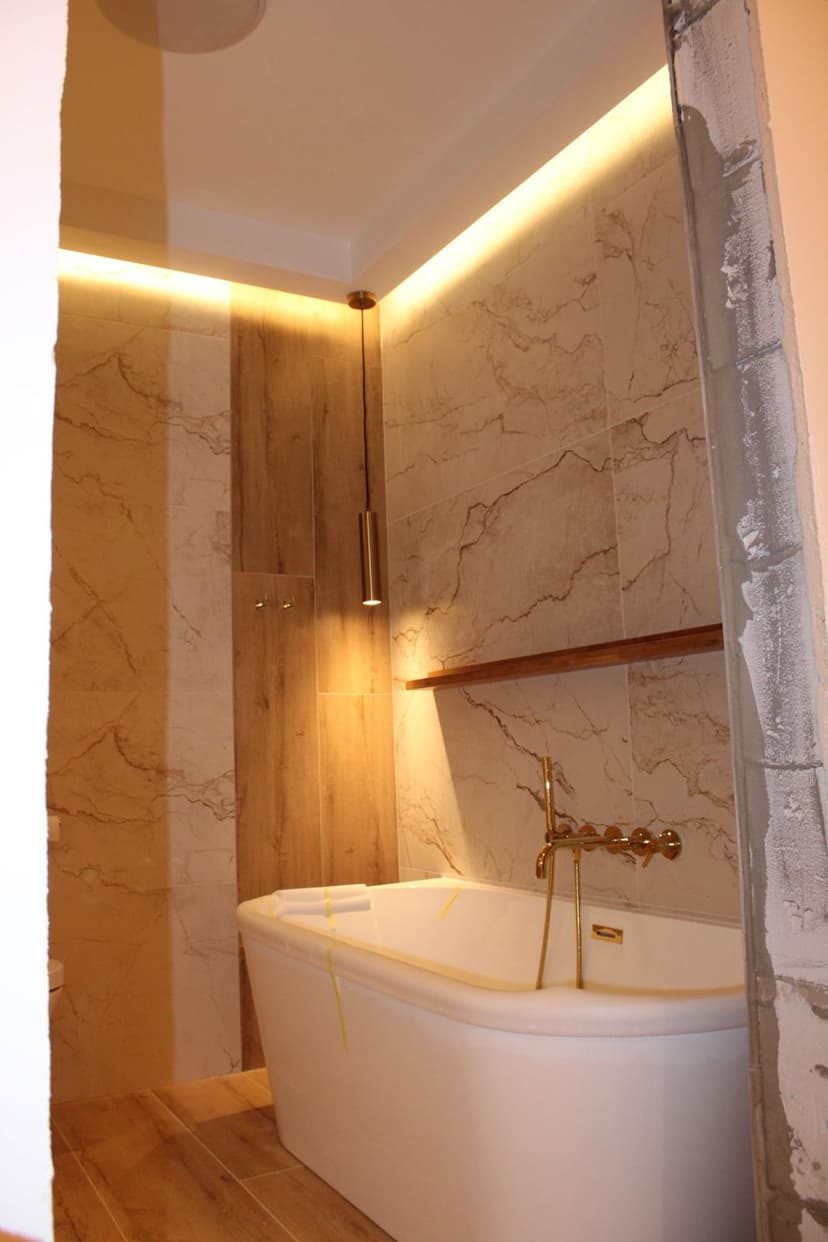 Biała wanna ze złotą armaturą w oświetleniu typy `ambient`.