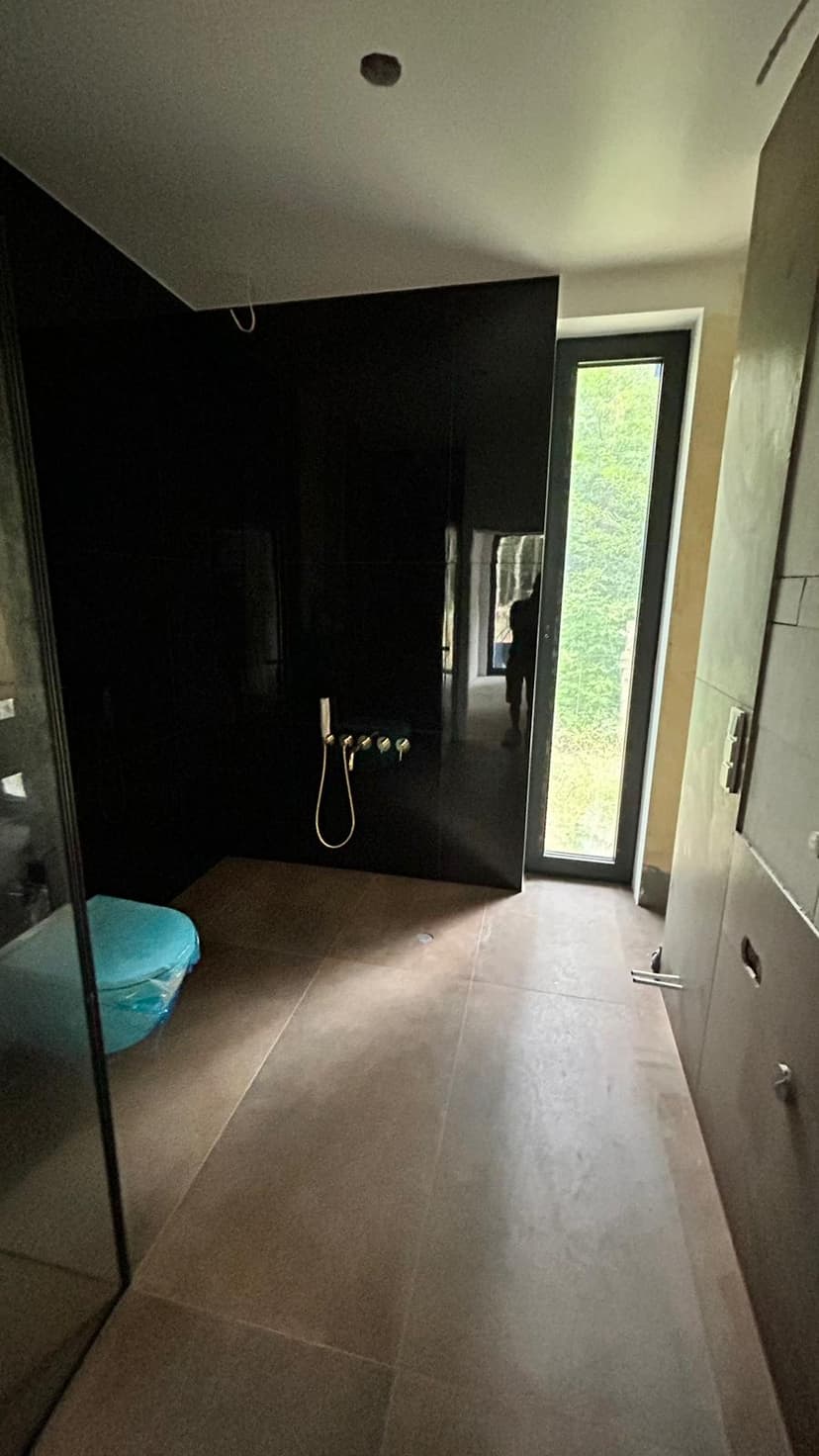 Czarna łazienka przygotowana do montażu kabiny prysznicowej typu `walk-in`.