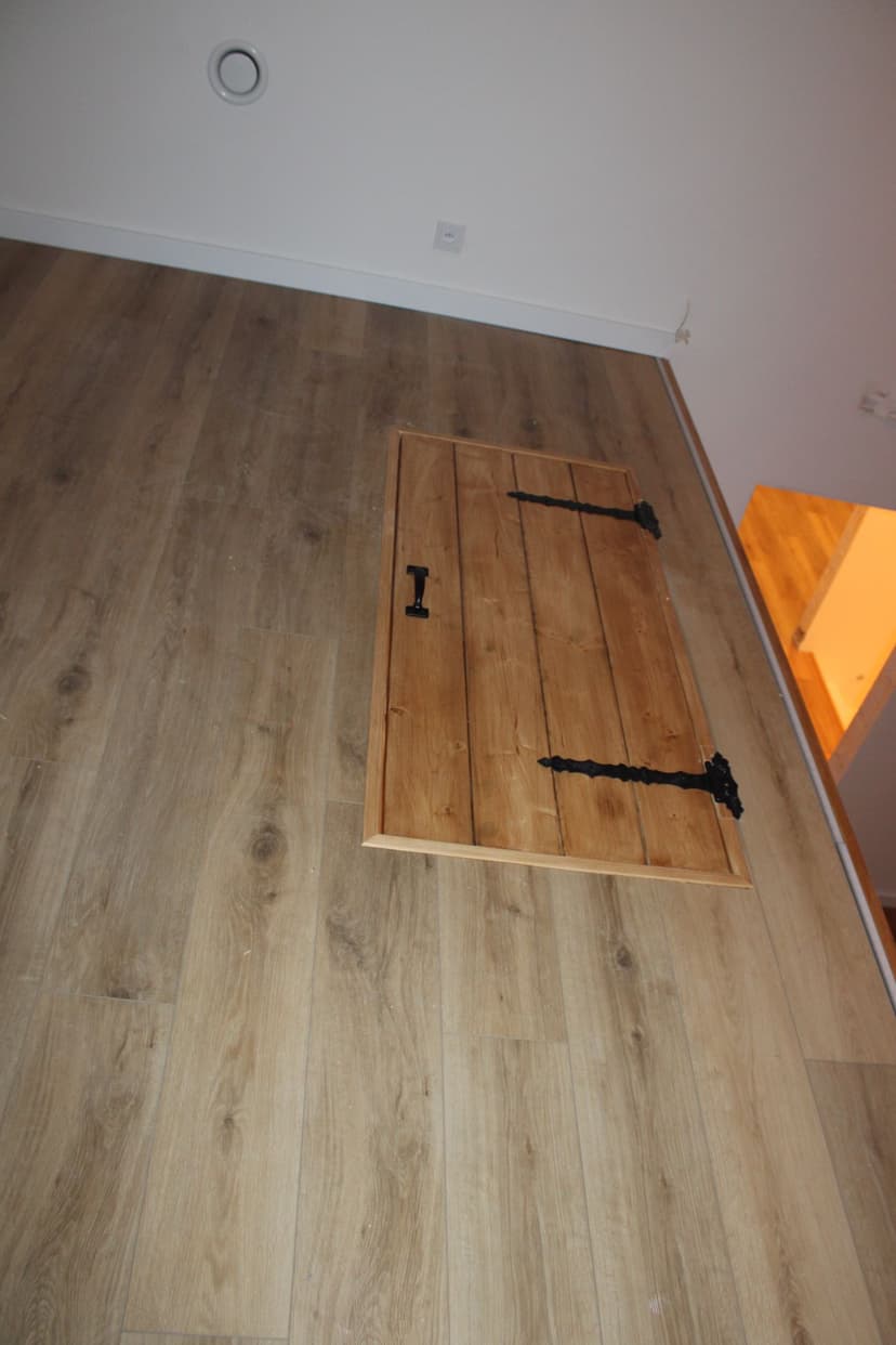 Wejście z antresoli na schody, zamontowane uchylne drzwiczki z metalowymi czarnymi zdobionymi okuciami.